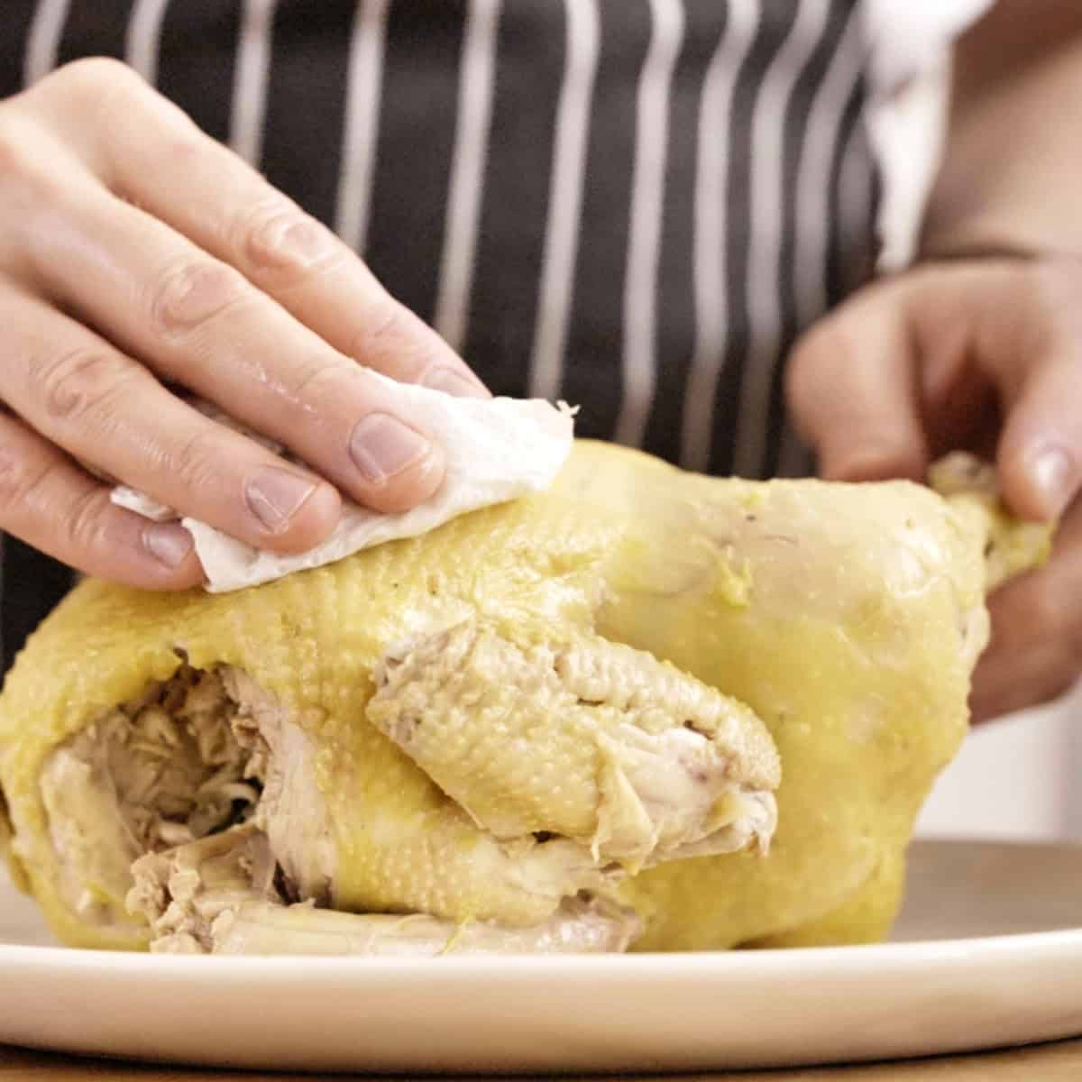 Drying poached chicken with paper towel.