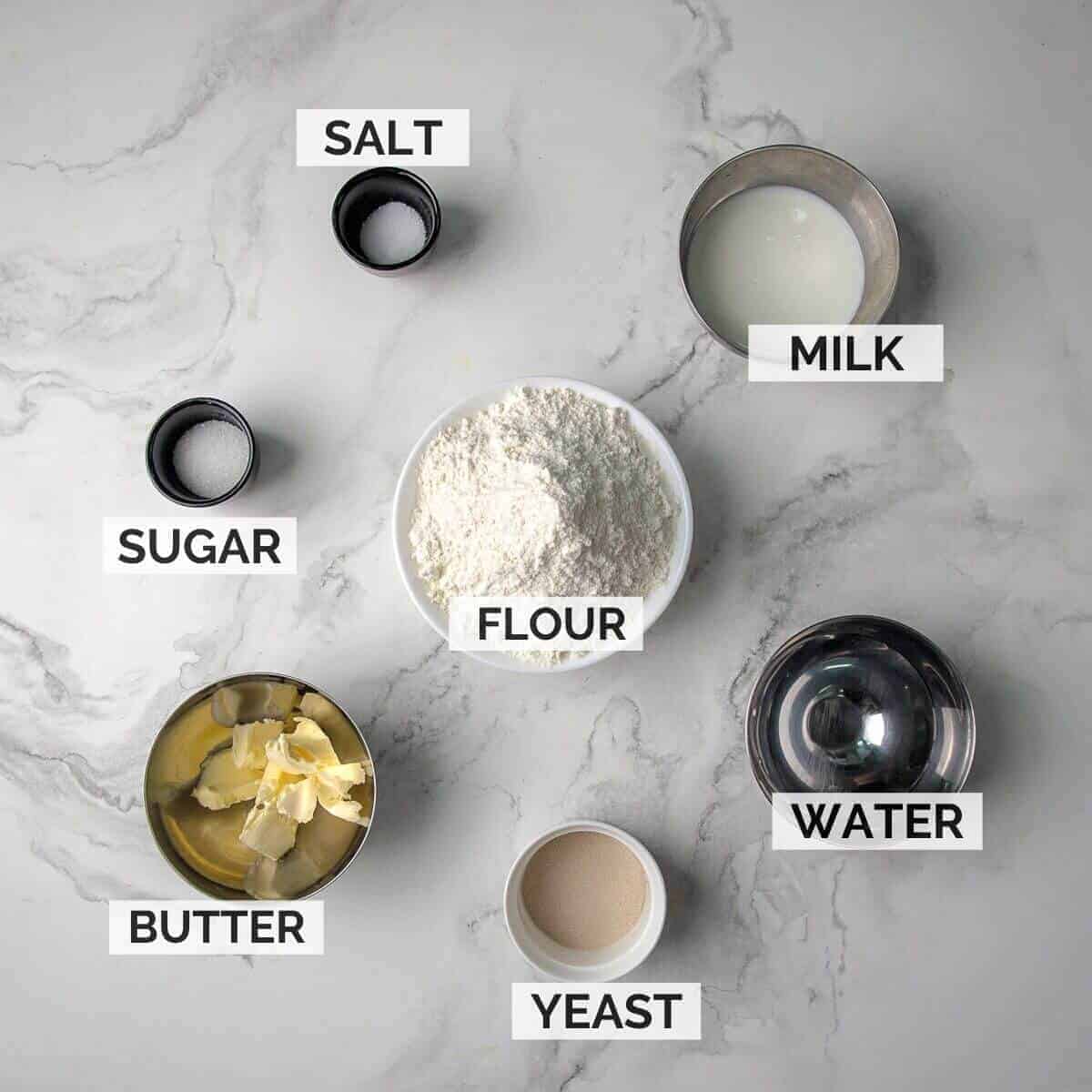 Ingredients for making English muffins on a marble surface.