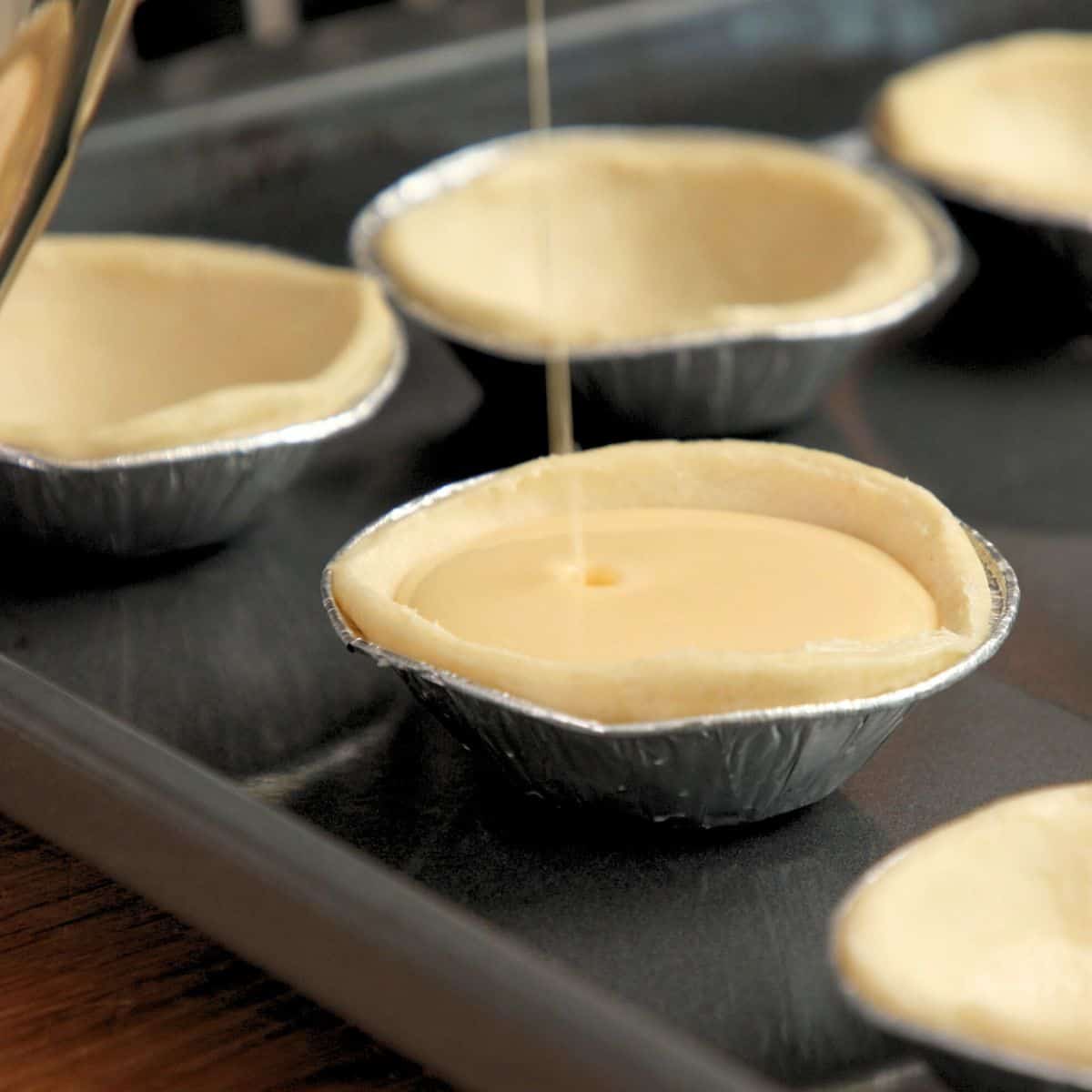 Filling tart cases with custard.