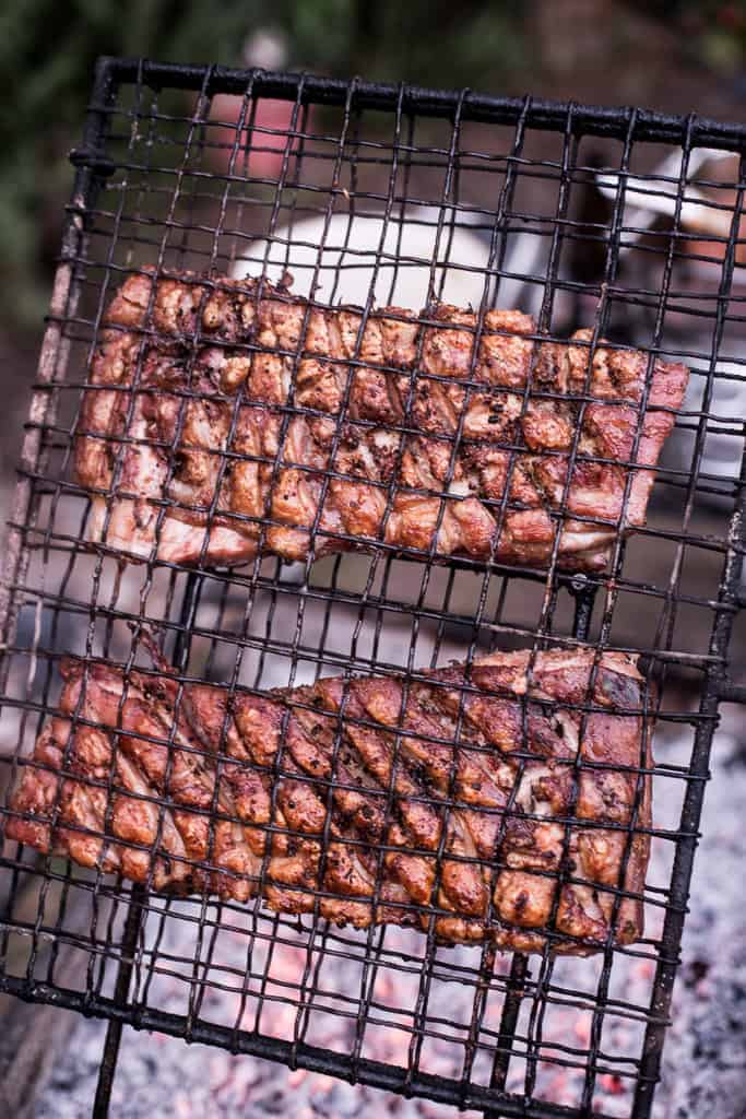 crispy pork belly on black grill over hot embers