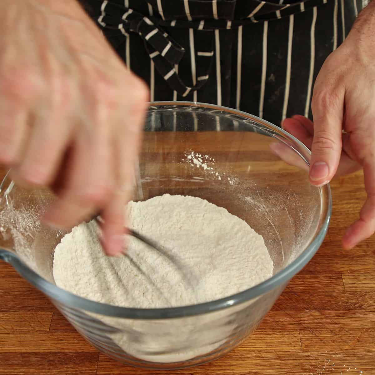 Flour and salt whisked together in large mixing bowl with whisk beside it