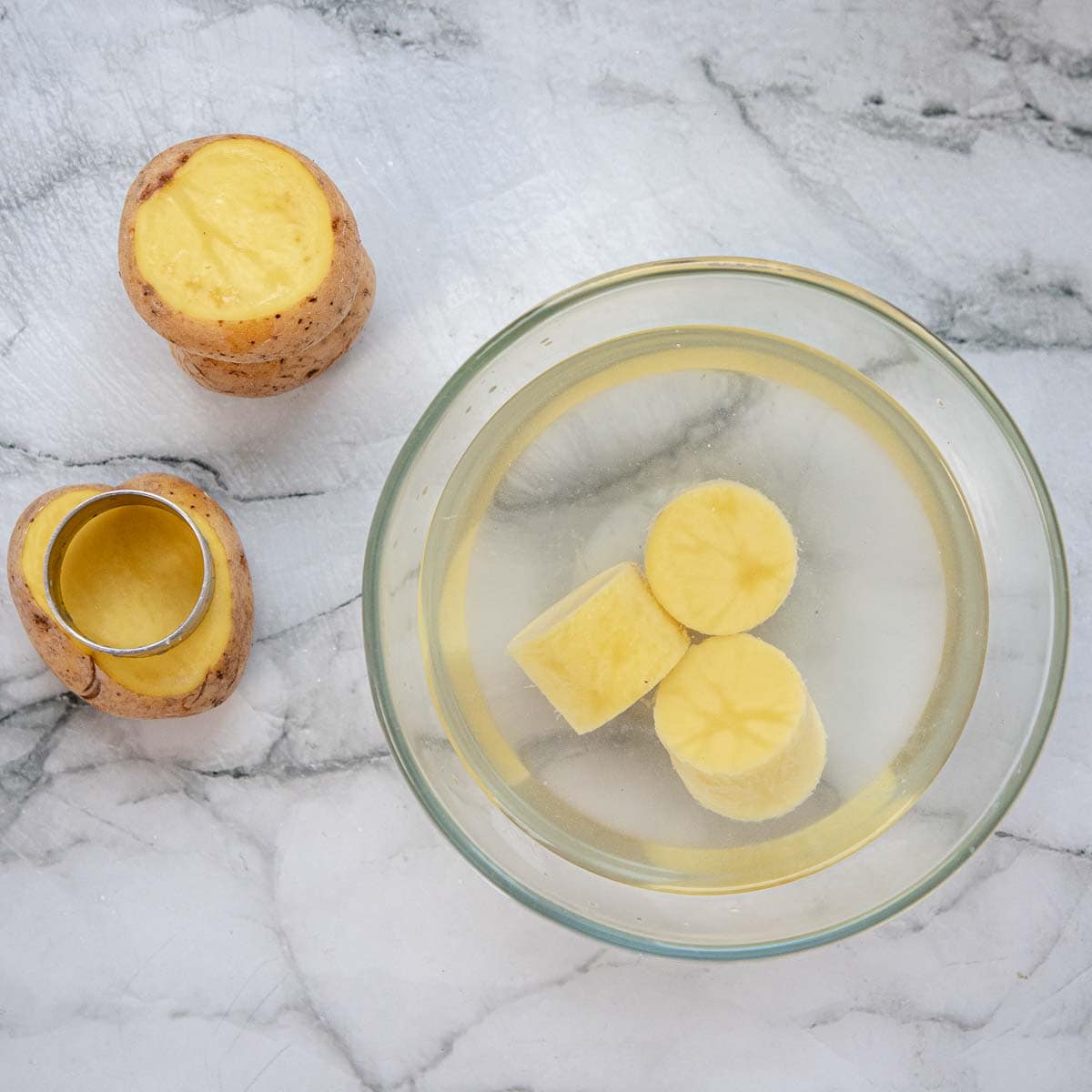 Potato cylinders in water for making fondant potatoes.