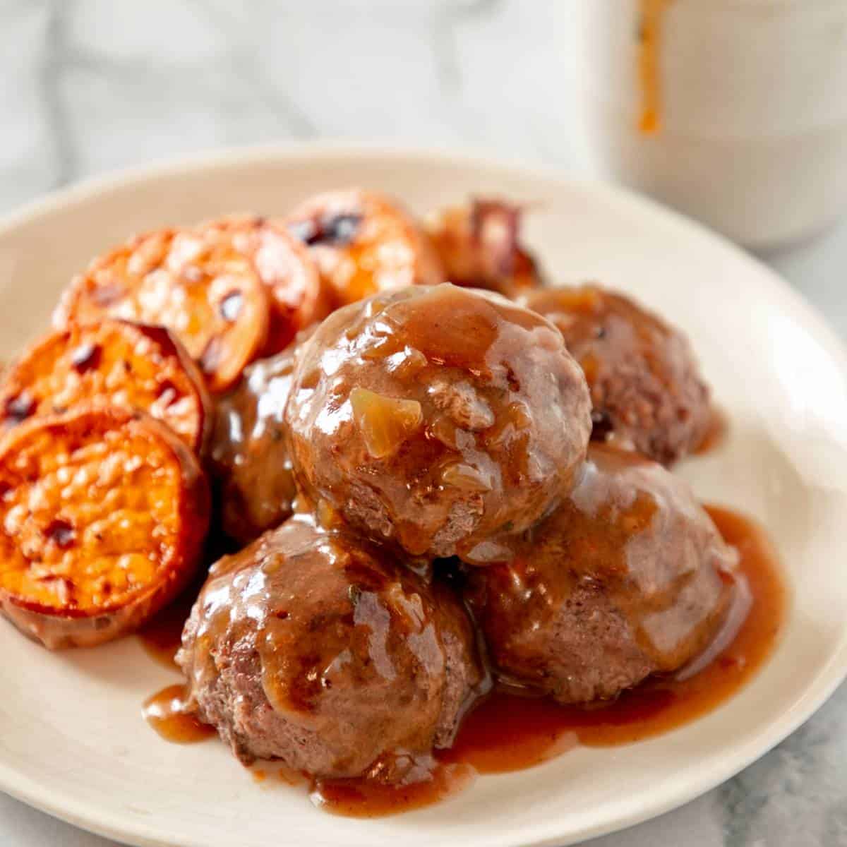 Frikkadels on a white plate with sweet potato.