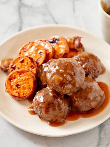 Frikkadels on a white plate with sweet potato.