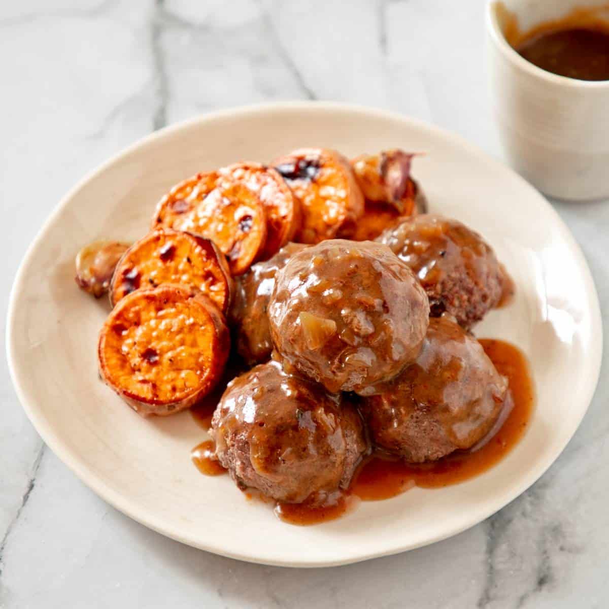 Frikkadels on a white plate with sweet potato.