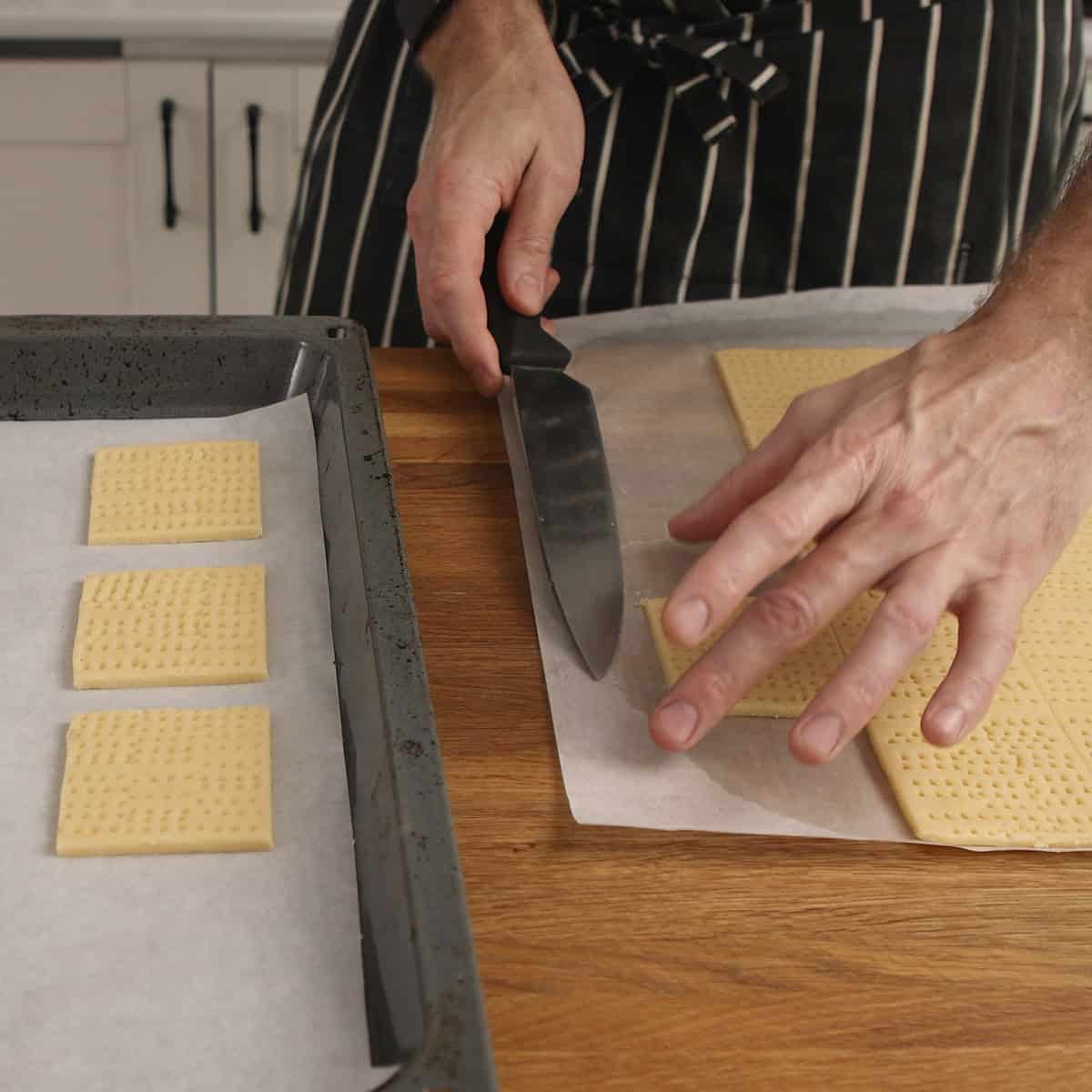 Cutting dough squares and placing onto a parchment lined tray.