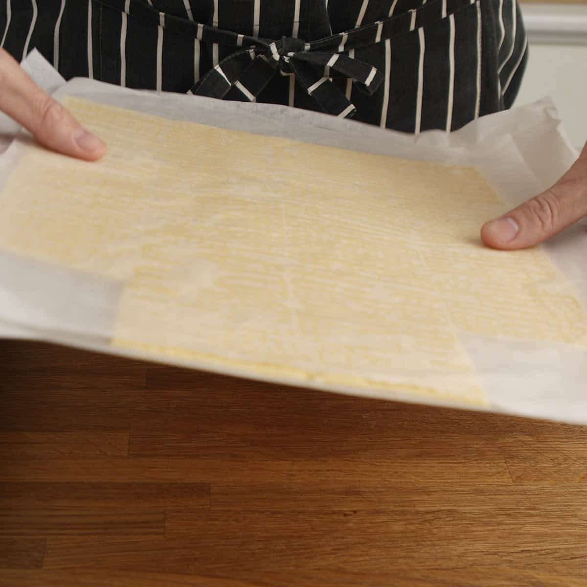Frozen tennis biscuit squares between layers of parchment.