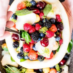 fresh fruit salad bowl with melon, berries, cherries , mint and dill blossom