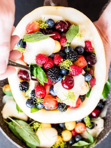 fresh fruit salad bowl with melon, berries, cherries , mint and dill blossom