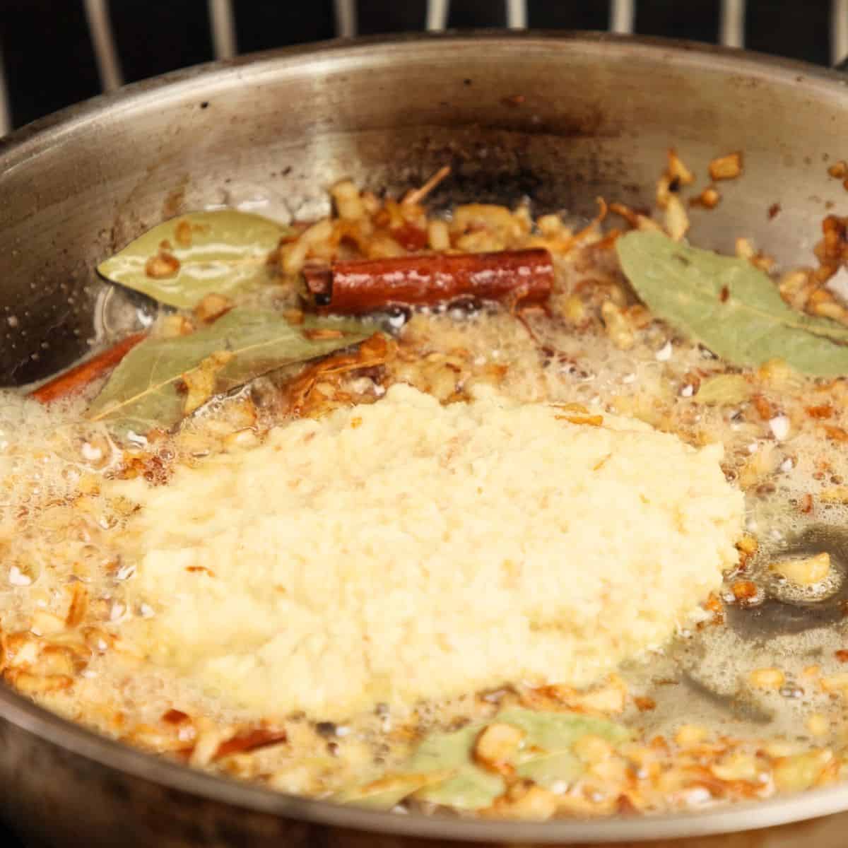 Adding ginger and garlic paste to caramelized onions and bloomed spices.