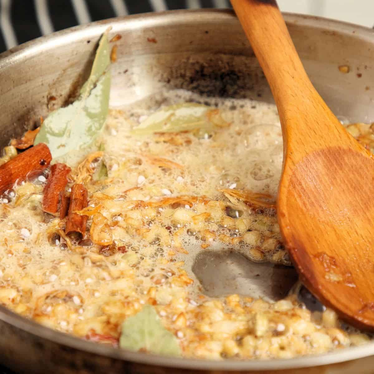Cooking whole spices with chopped onions.