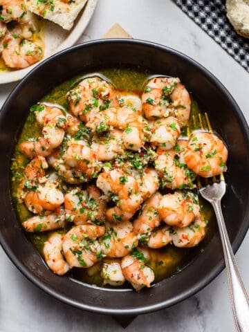 garlic butter shrimp in black bowl on marble table