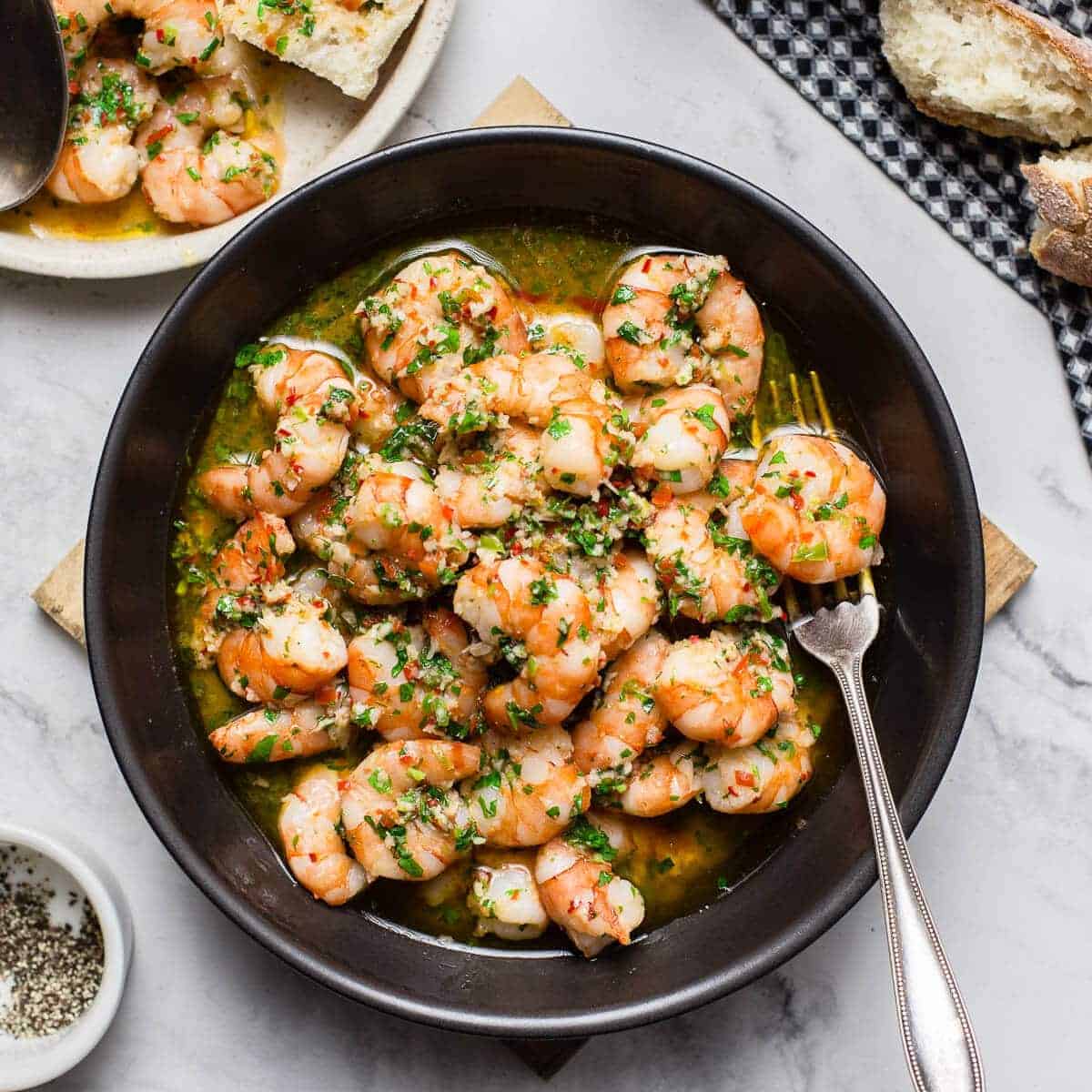 garlic butter shrimp in black bowl on marble table