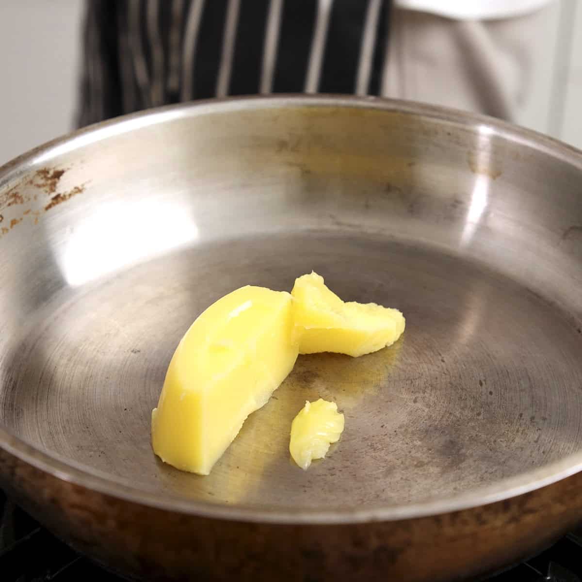 Ghee or clarified butter in a stainless steel pan.
