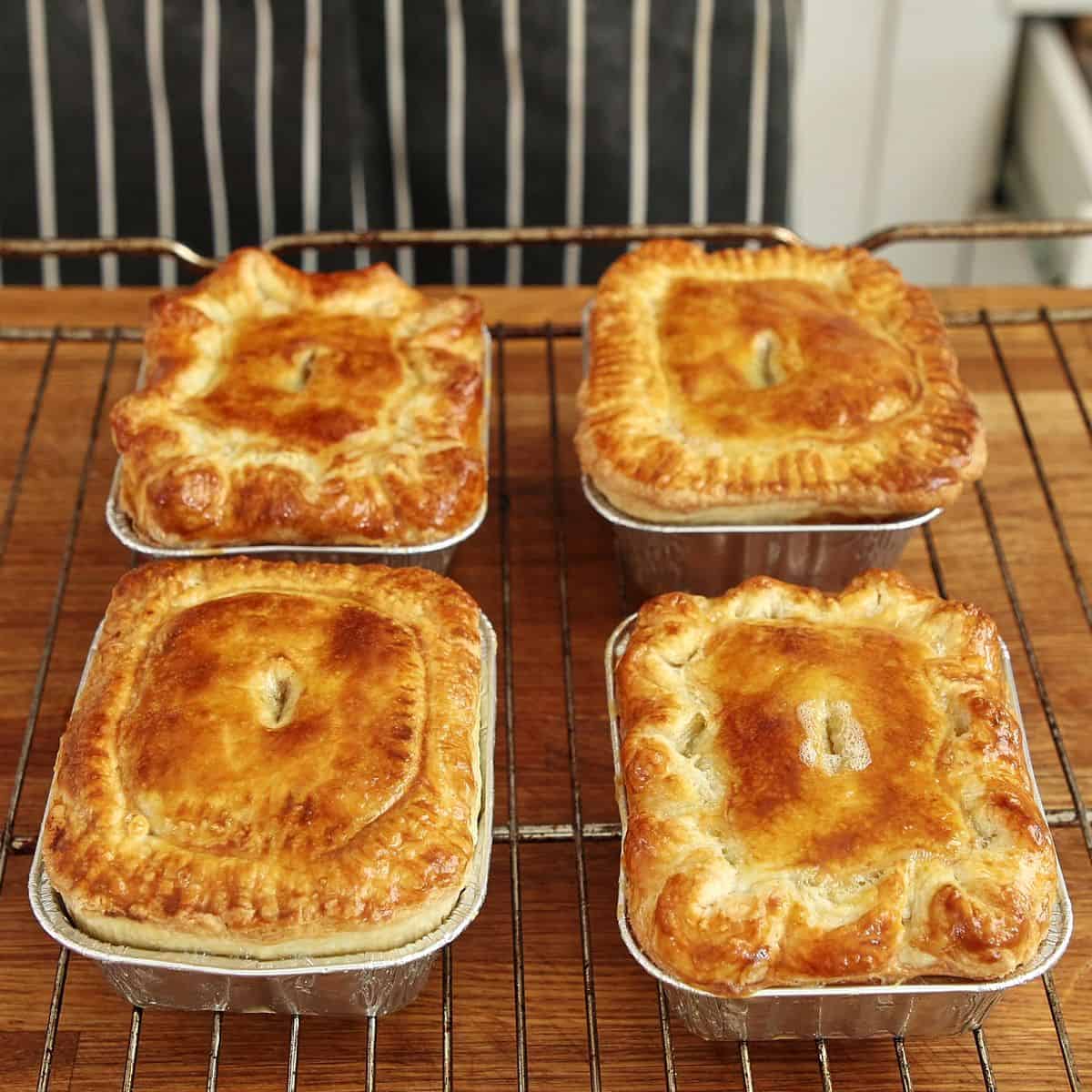 Golden brown baked pepper steak pies with blistered glossy tops just out of the oven