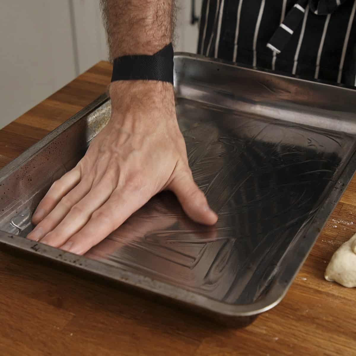 Oiling a tray by hand.