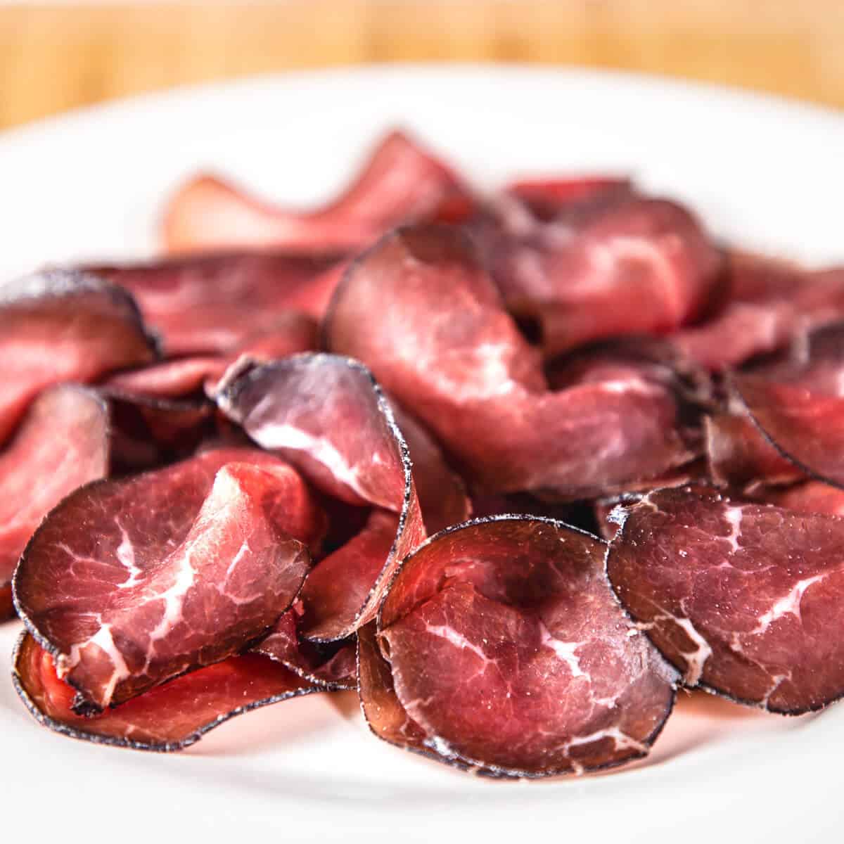 sliced cured beef bresaola on white plate