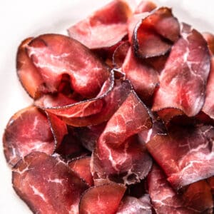 sliced cured beef bresaola on white plate