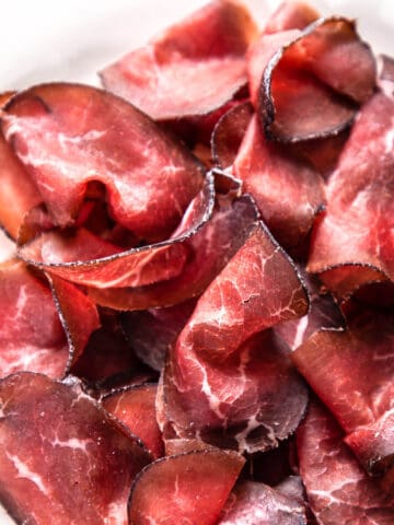sliced cured beef bresaola on white plate