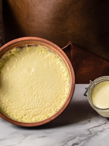 clotted cream in ceramic dish and glass jar on marble background