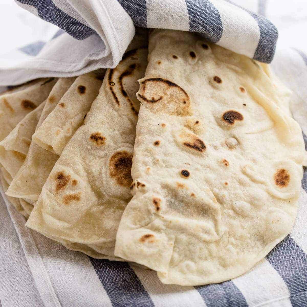 Homemade flour tortillas on blue and white mexican kitchen towel