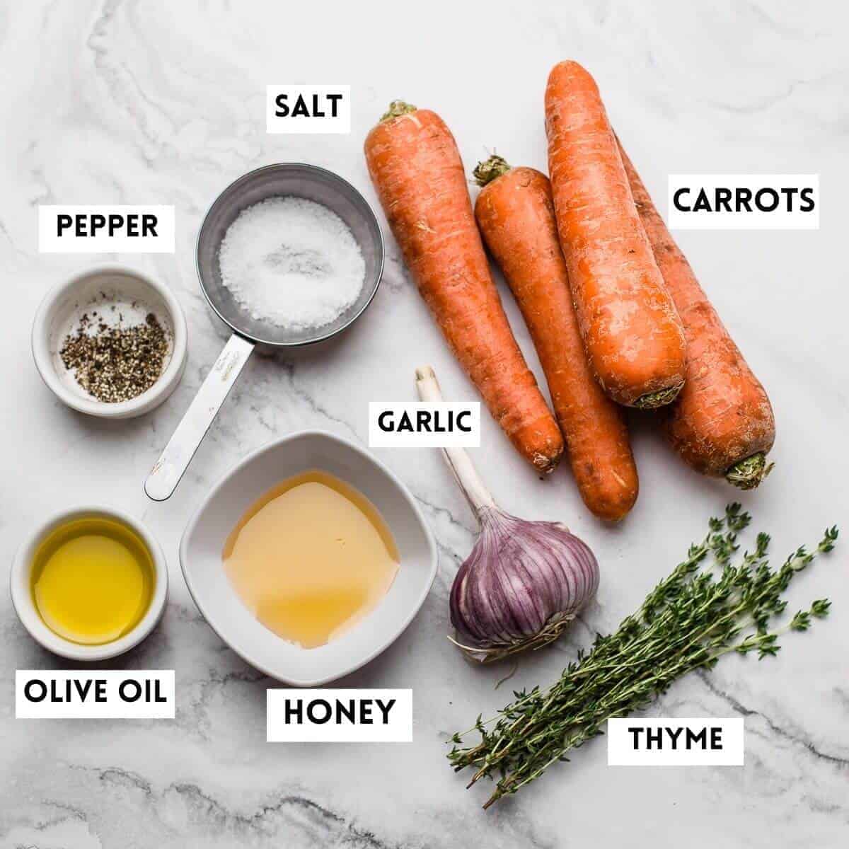 ingredients needed on marble. carrots,honey,garlic,thyme,salt,oil,pepper