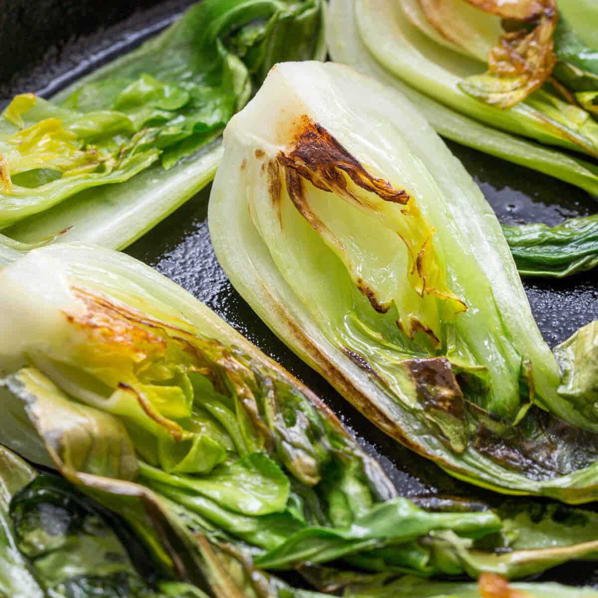 bok choi cooking in a black cast iron skillet.