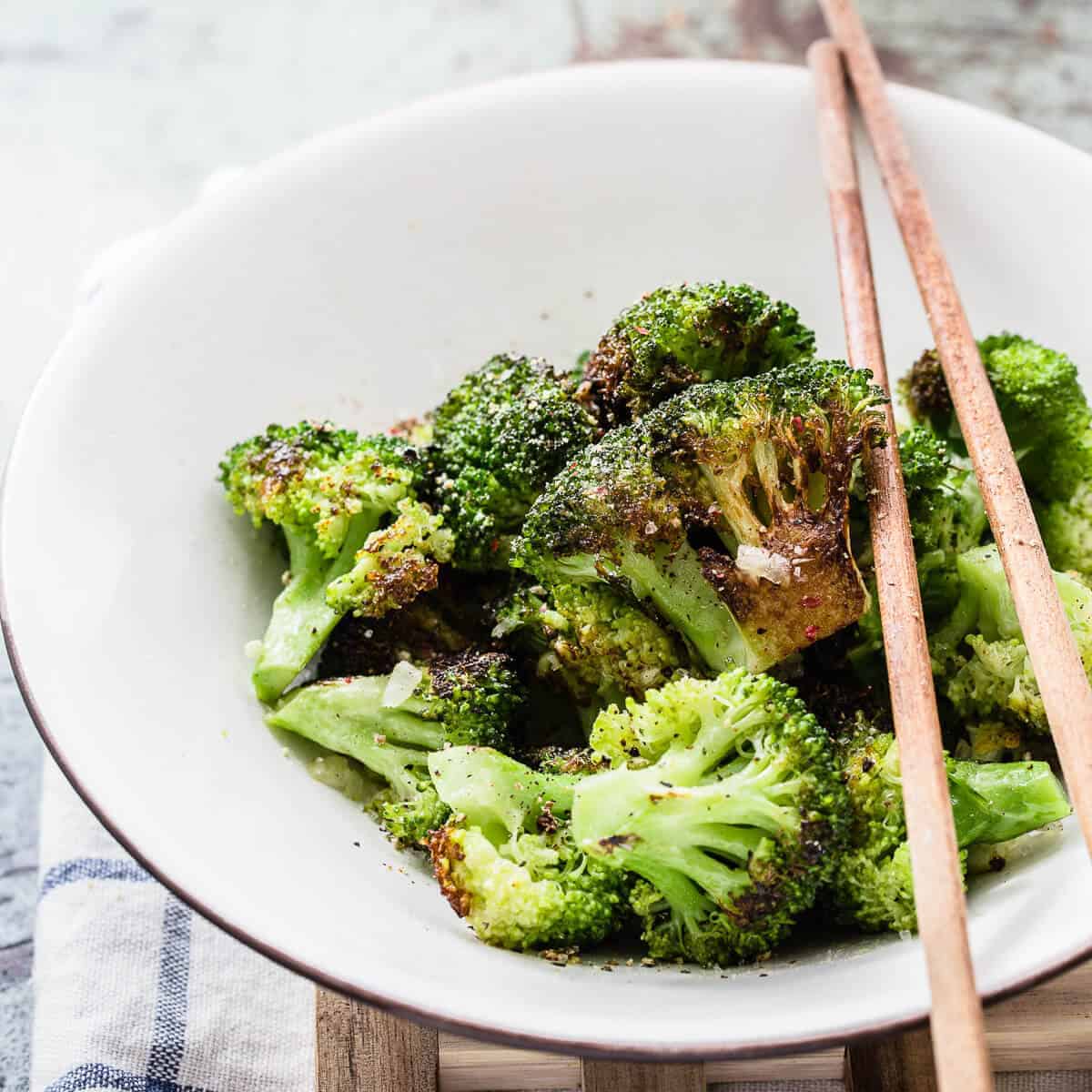 cooked broccoli in a bowl with chopsticks