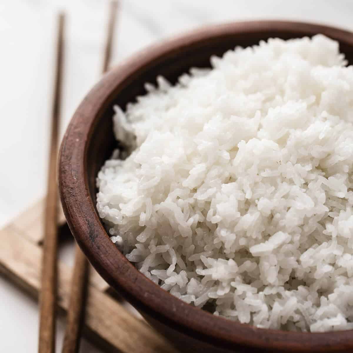 white steamed rice in brown bowl with chopsticks