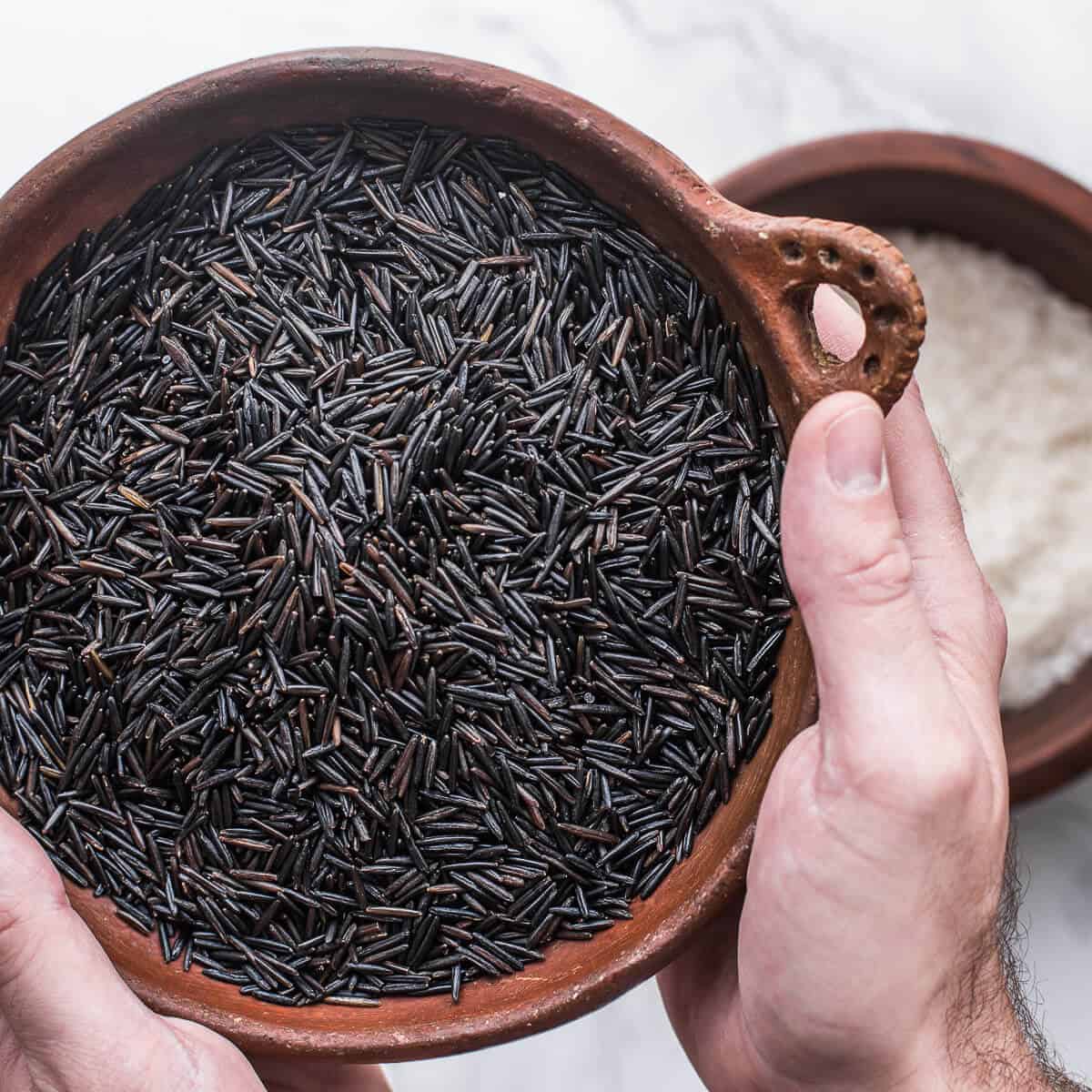 Raw wild rice o
in a brown bowl.