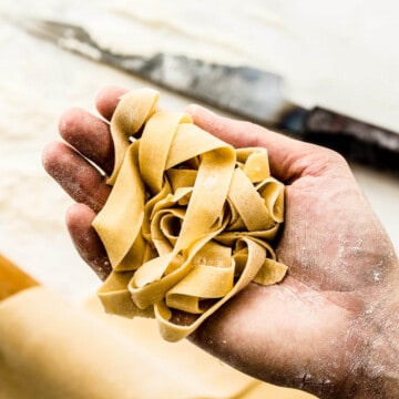 Freshly made hand cut pasta dough in a hand.