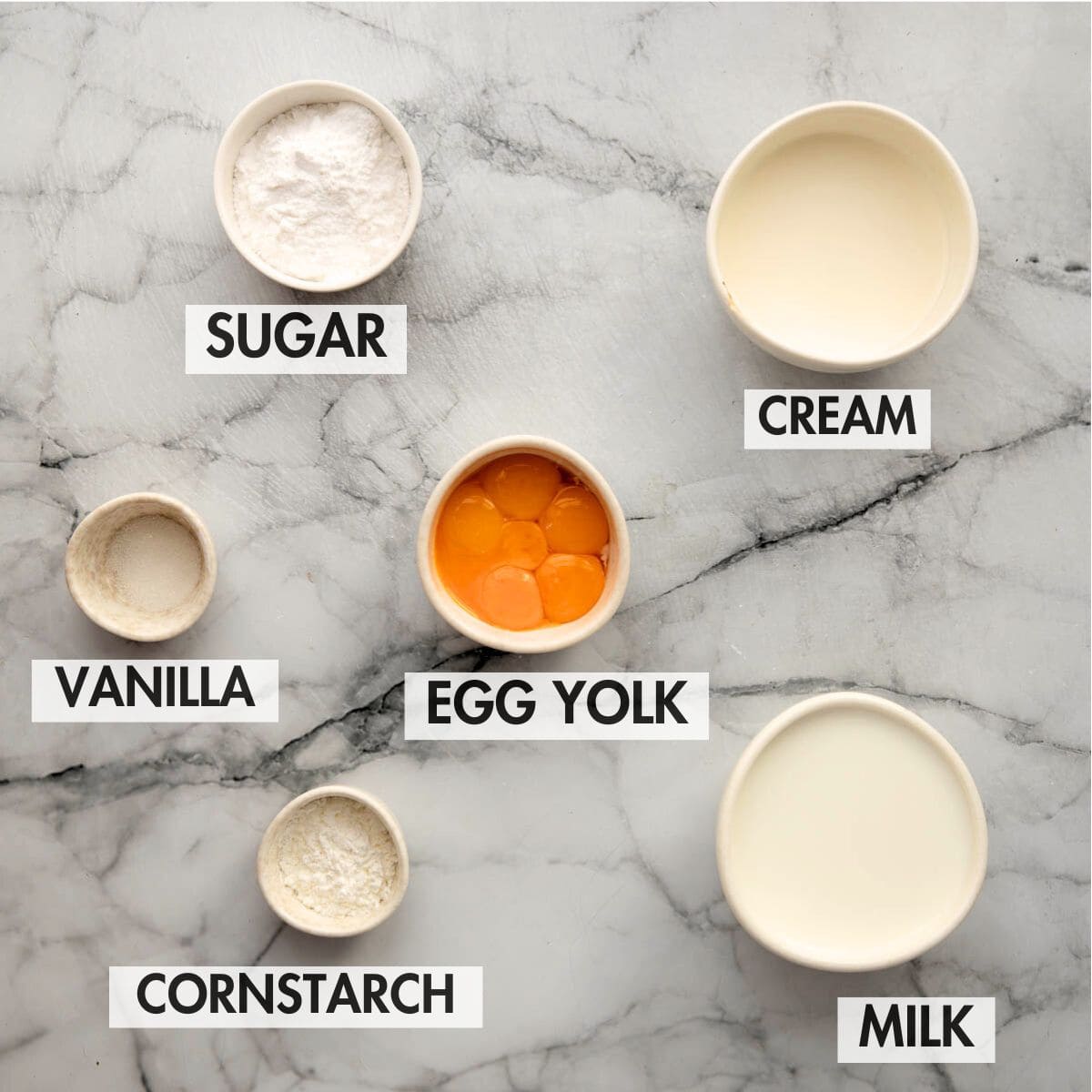 Ingredients for homemade custard on a marble surface.