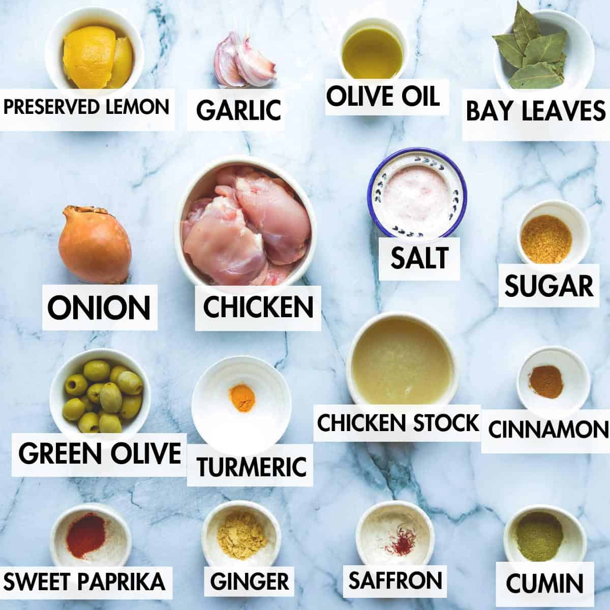 Ingredients for making Moroccan lemon chicken on a marble background.