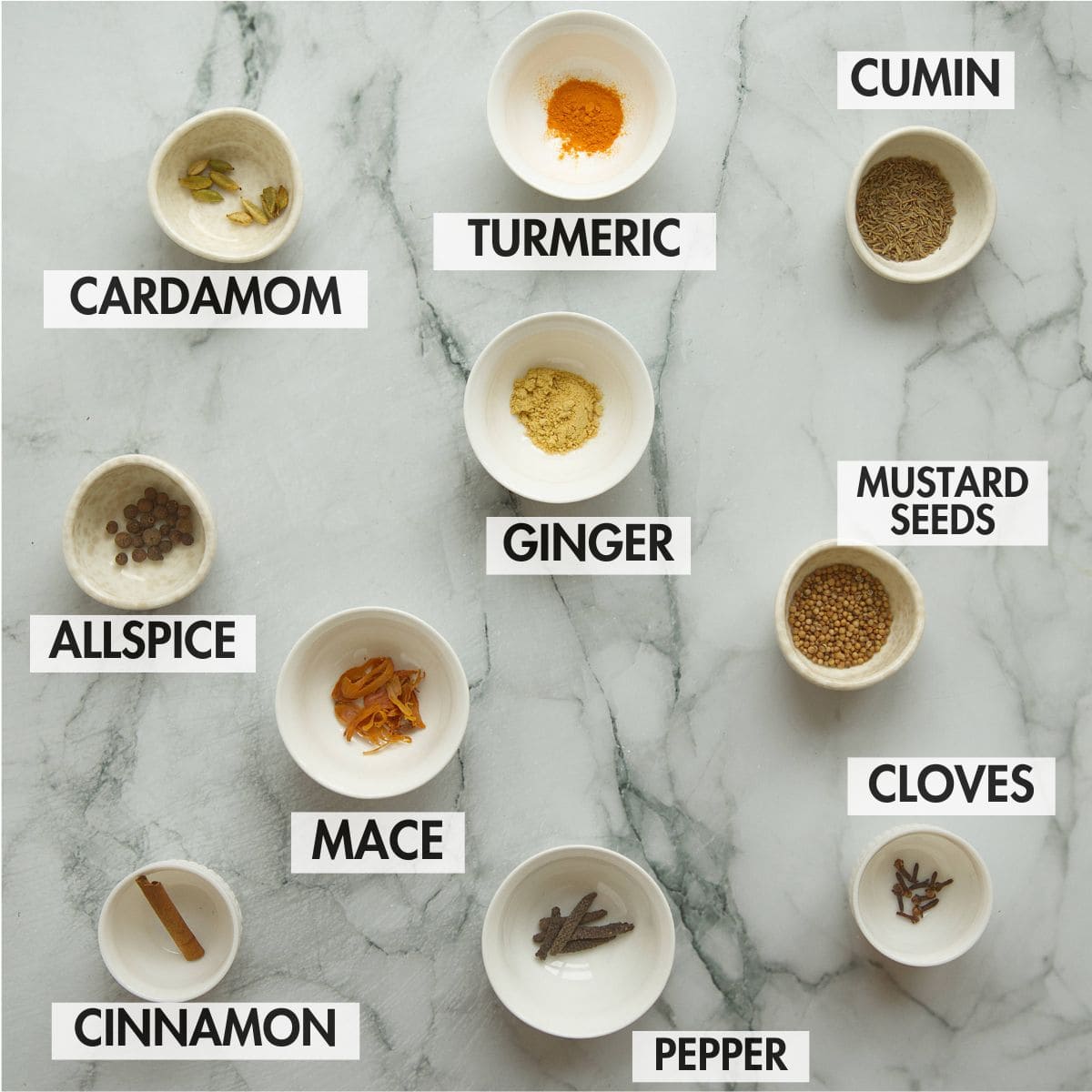 Spices for ras el hanout on a marble surface.