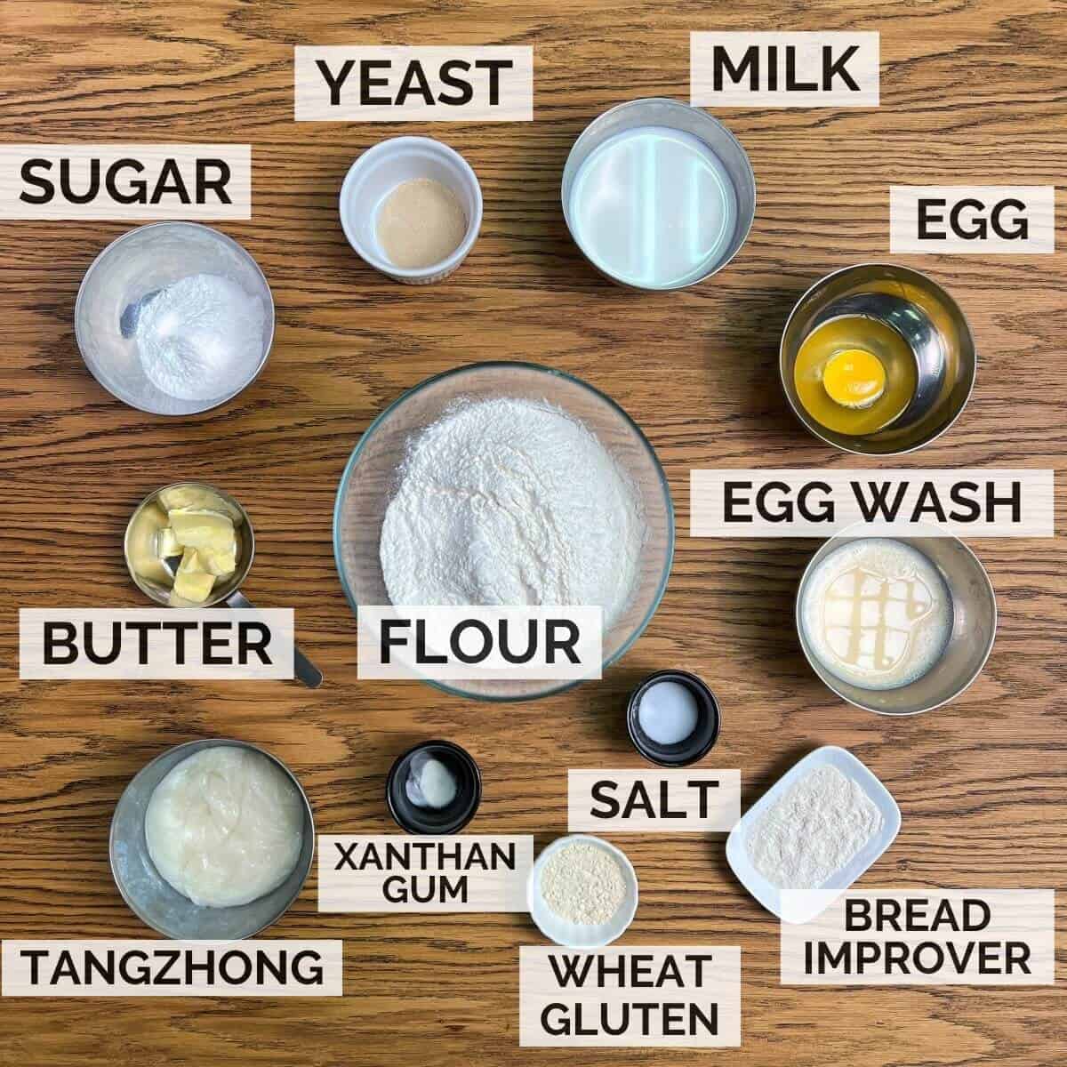 Labeled ingredients for making soft milk buns on wooden table.