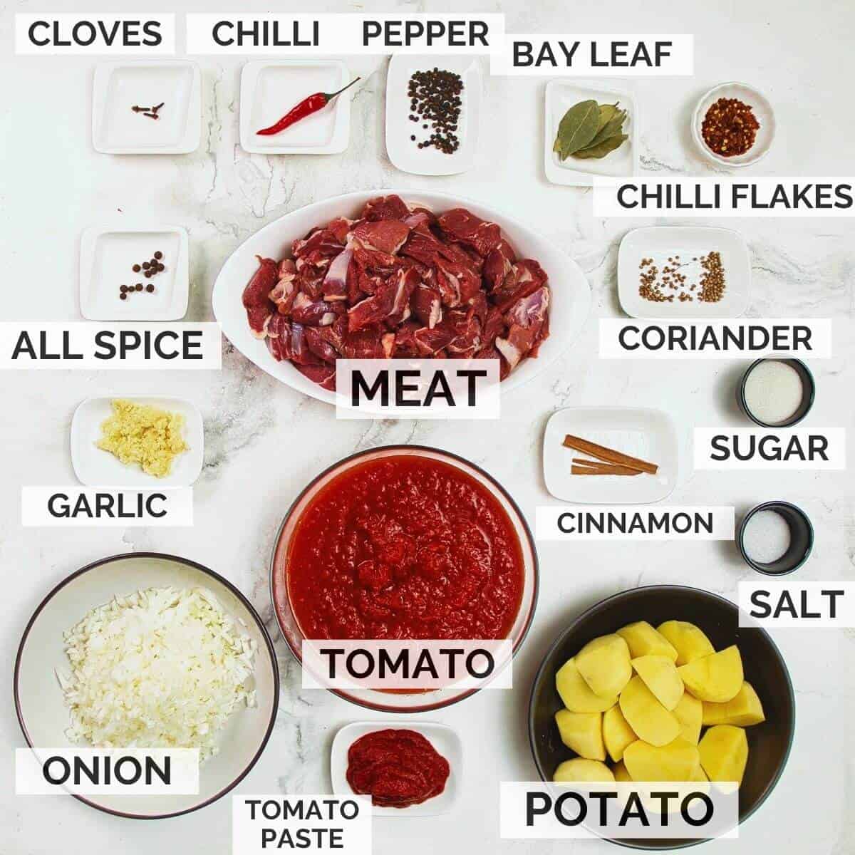 Ingredients needed for making tomato bredie on a marble background.