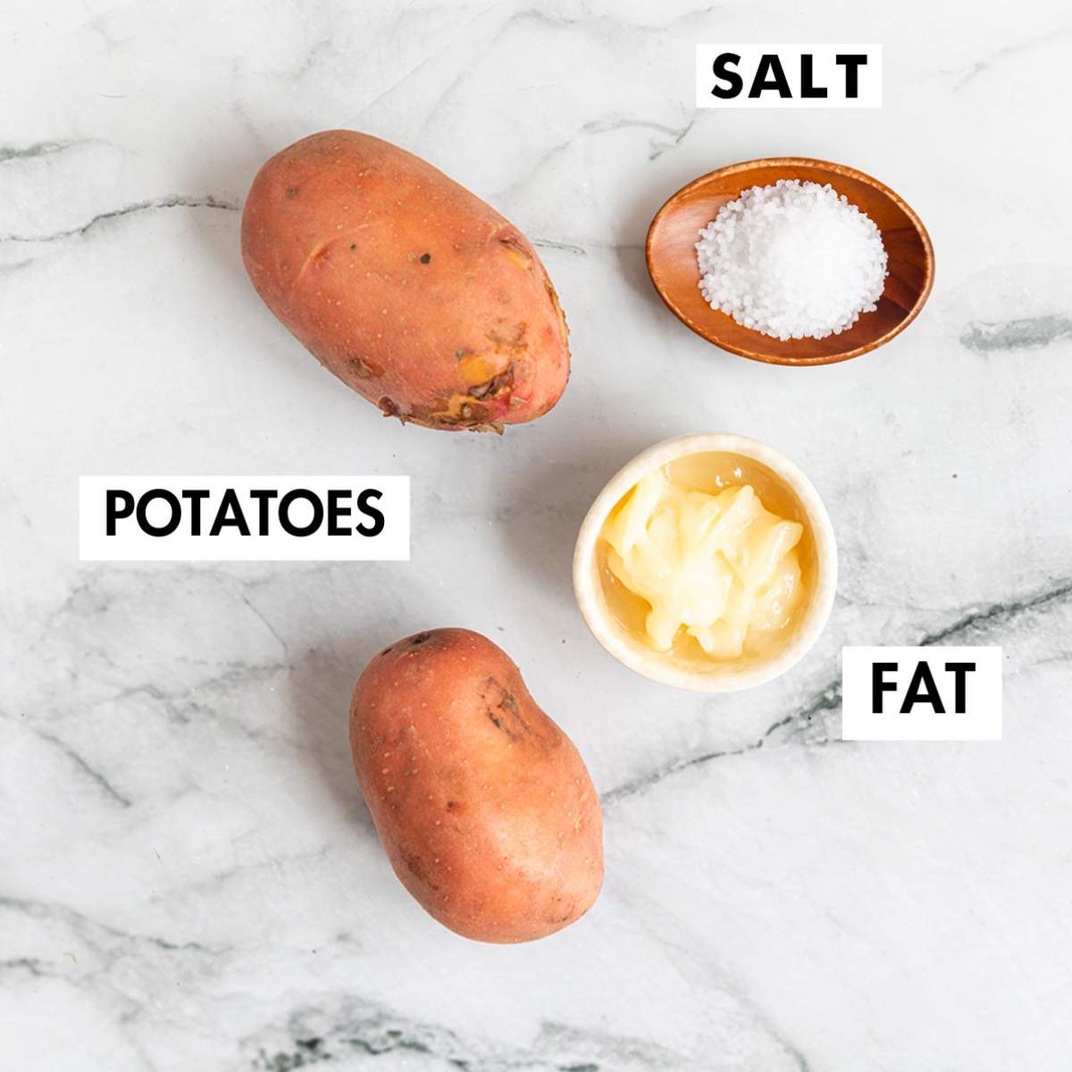 Ingredients for making roasted potatoes on a marble board.