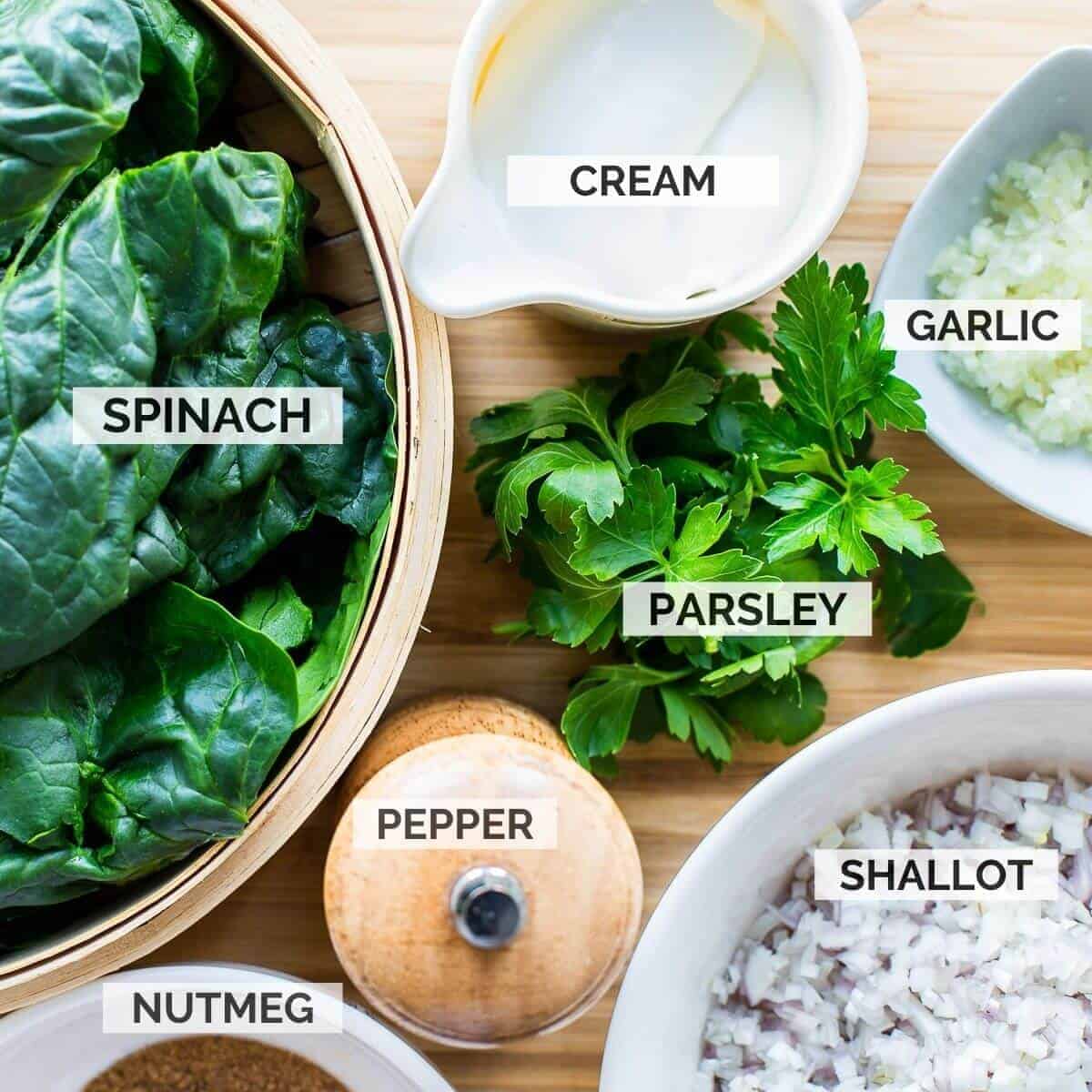 ingredients for making creamed spinach on a wooden board.