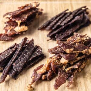 Beef and pork jerky on a wooden board.