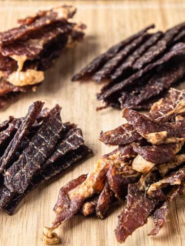 Beef and pork jerky on a wooden board.