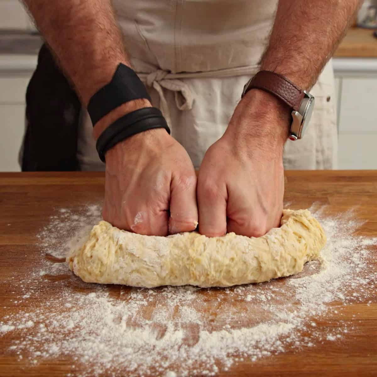 Kneading pelmeni dough on floured surface.