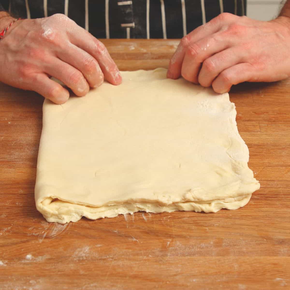 Folding pastry with putter on table.