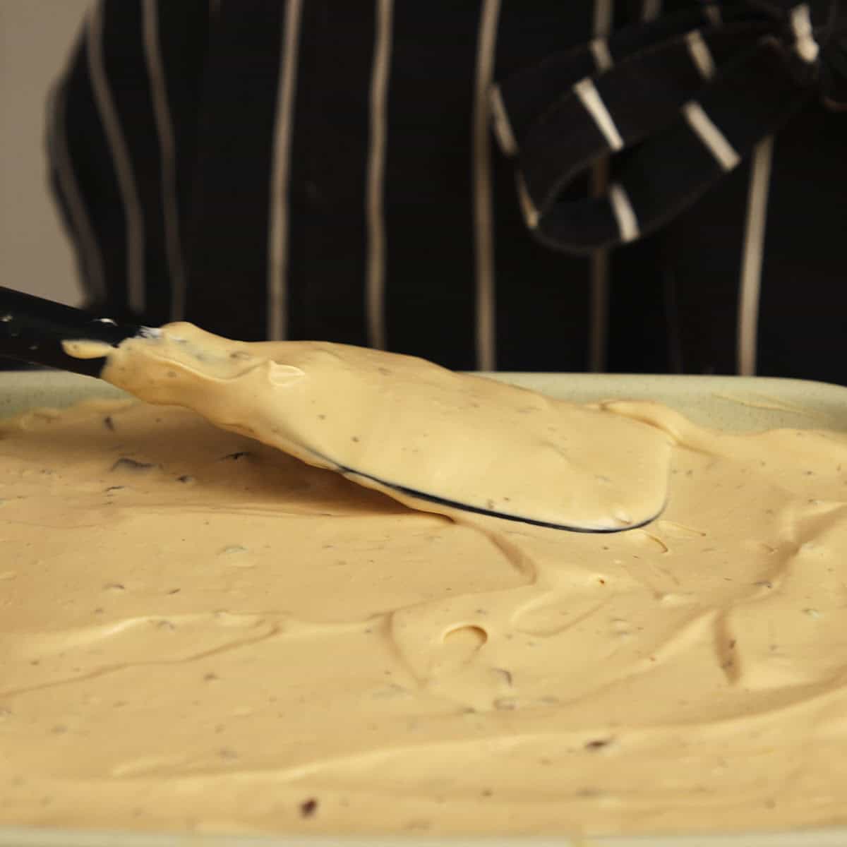 Spatula leveling cream in green dish.