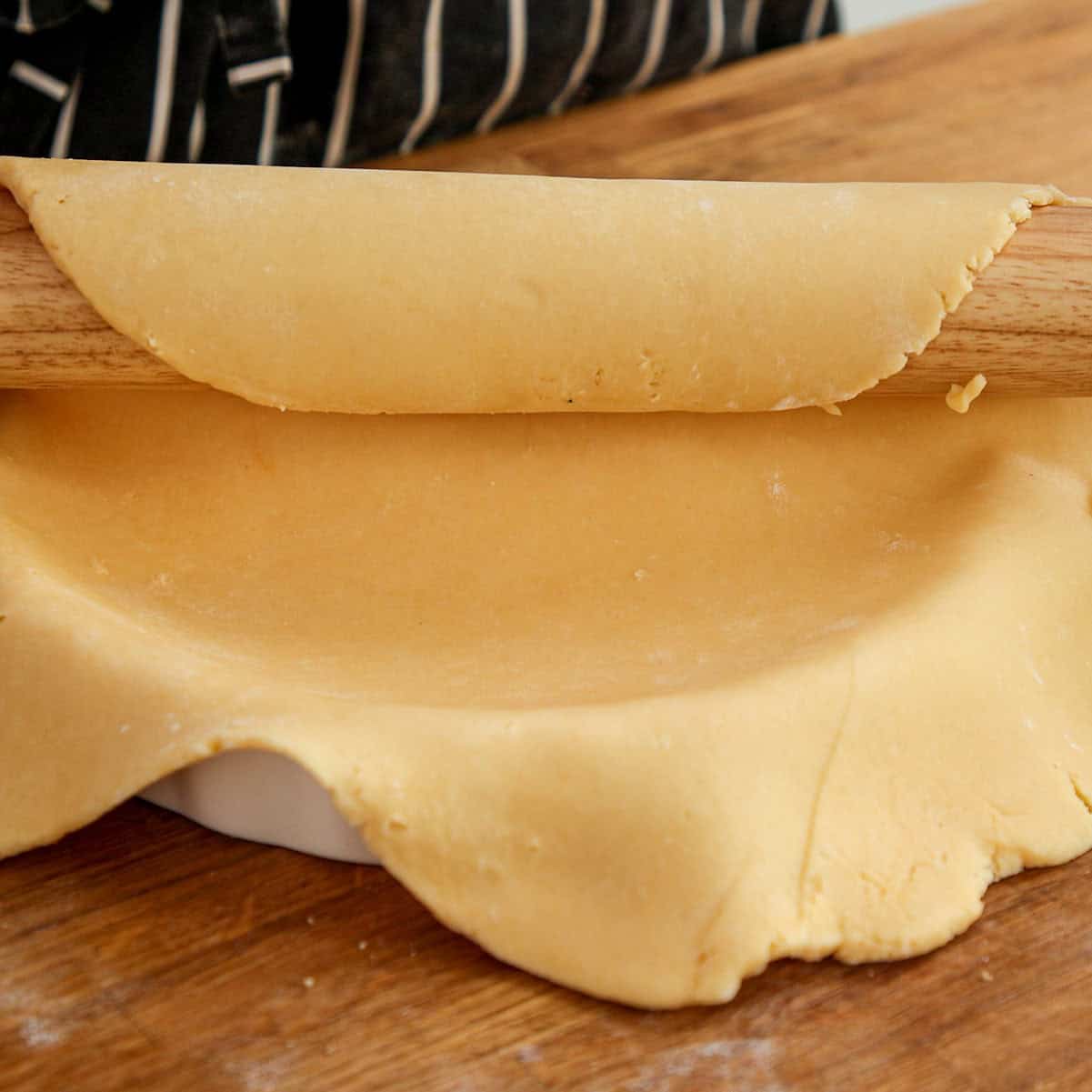 Lining tart case with pastry for baking.