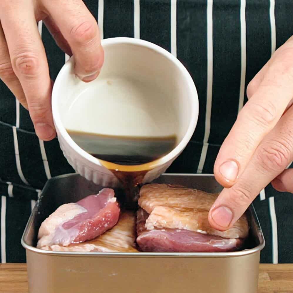 Pouring marinade over salted duck breasts.