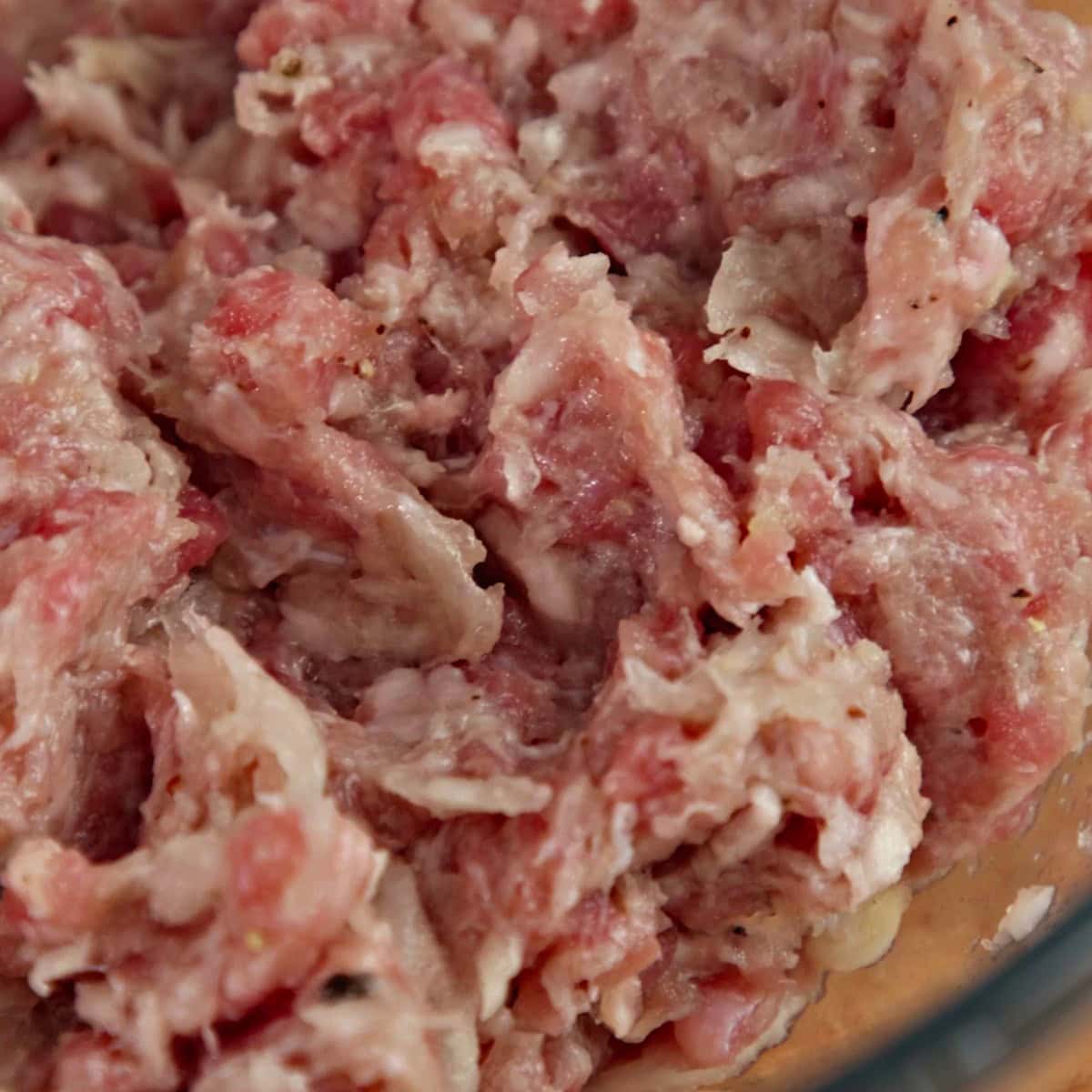 Prepared meat filling in a glass bowl.