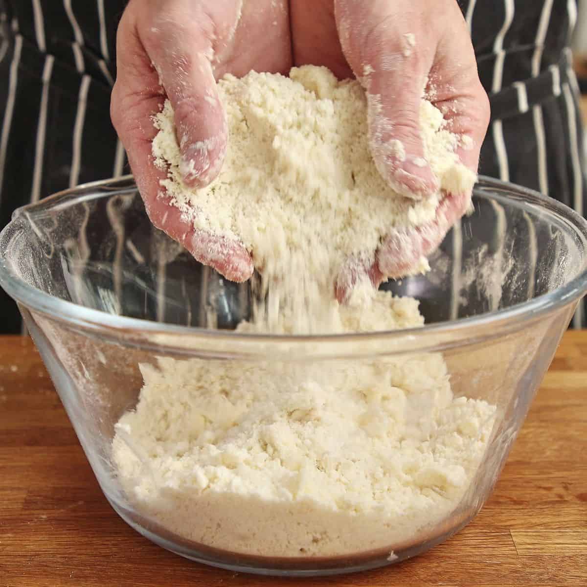 Melted butter rubbed into flour mixture, texture becoming sandy and crumbly