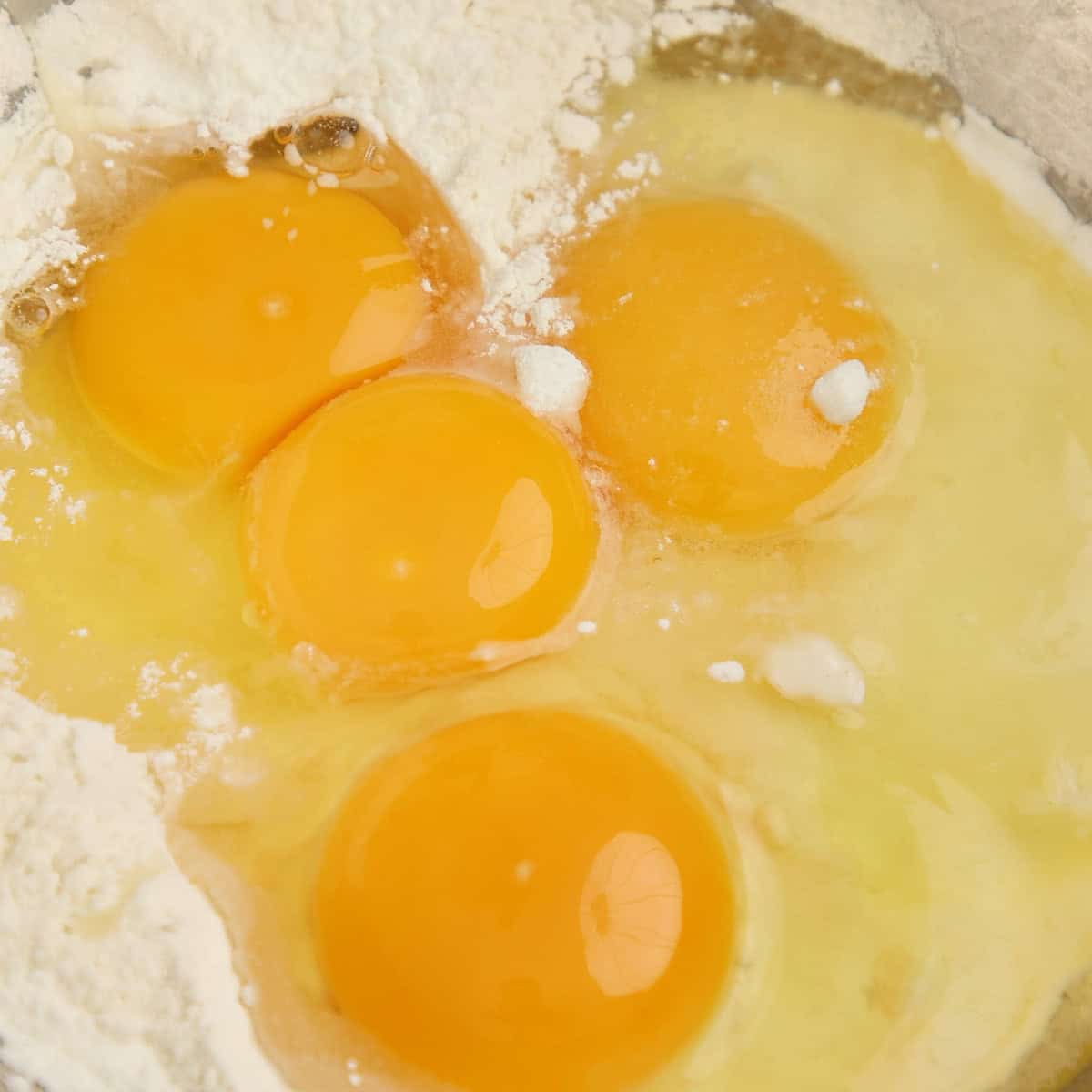 Cracked eggs and melted butter mixed into flour in a bowl.