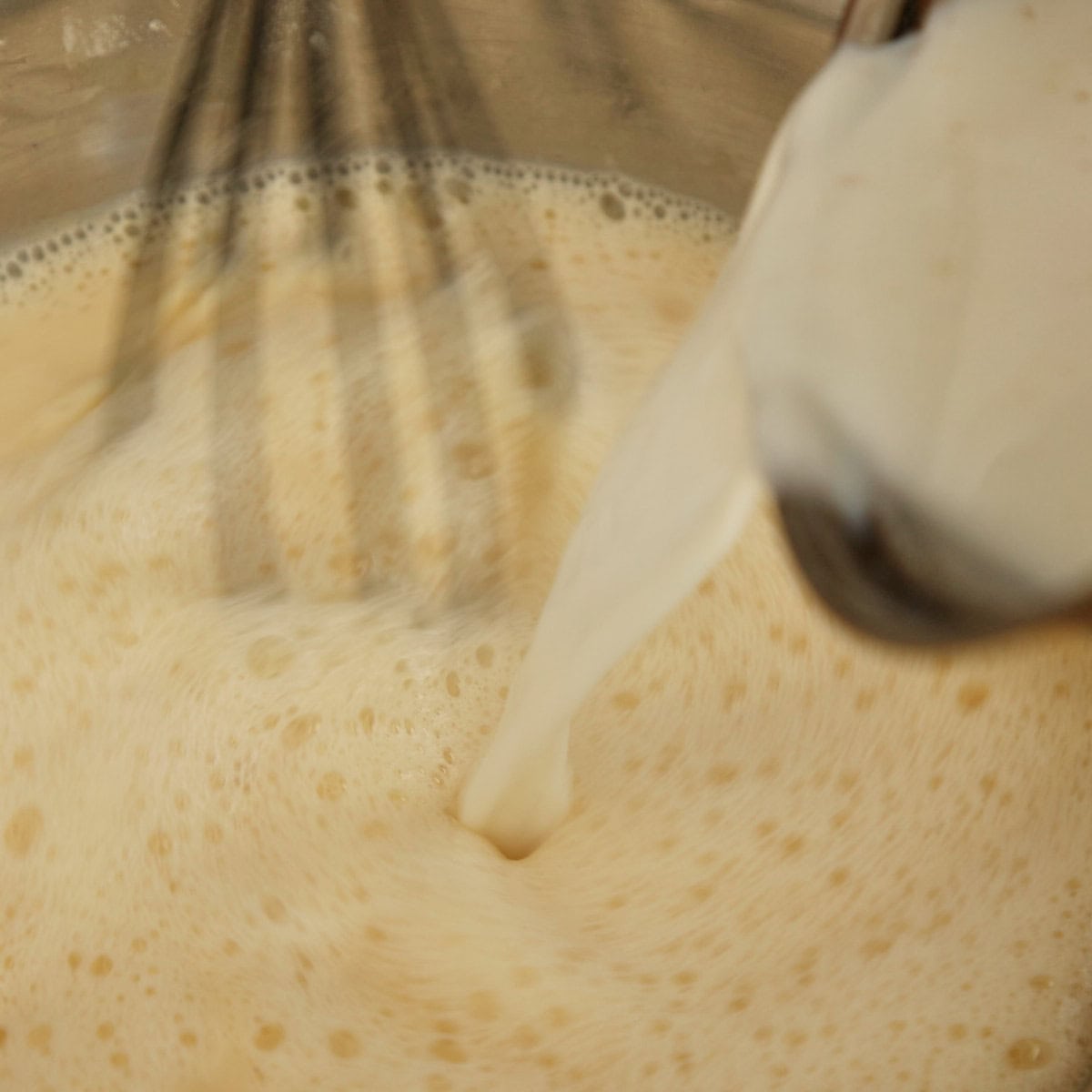 Pouring hot milk infusion into egg mixture.