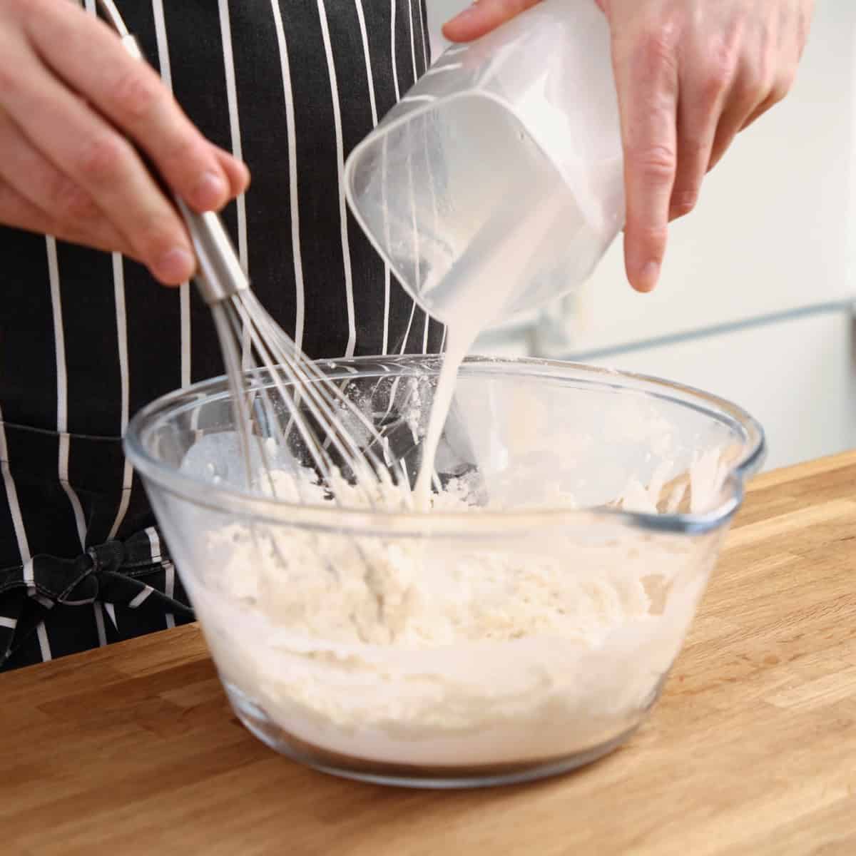 Adding milk to flour.